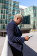 © David Munoz/ADDICTIVE STOCK - Side view of smiling African American businessman standing in downtown and browsing tablet online