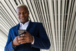 © David Munoz/ADDICTIVE STOCK - From below of elegant African American male entrepreneur browsing smartphone on street and checking business issues