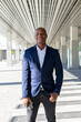 © David Munoz/ADDICTIVE STOCK - Cheerful black male entrepreneur in stylish formal outfit walking along sunny street and looking at camera