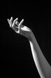 © Erika Anes/ADDICTIVE STOCK - Black and white of crop anonymous female with slim arm on dark background in studio reaching towards light