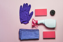 Top view of latex gloves and spray detergent arranged on pink background with sponges and rag for cleaning concept