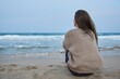 © German Linares/ADDICTIVE STOCK - Back view of unrecognizable female sitting on sandy shore and admiring amazing view of sea in evening