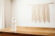 © Gustavo Pozo/ADDICTIVE STOCK - Full bottle of water placed on wooden table in light room with minimalist boho decor