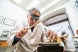 © Ioritz Lopez/ADDICTIVE STOCK - Low angle of focused skilled mature male master in glasses using hammer and chisel while working with gemstone in jewelry workshop