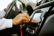 © Jake Jakab/ADDICTIVE STOCK - Side view of cropped unrecognizable African American male driver sitting in luxury car and setting radio for listening to music