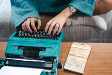 Crop View Of Anonymous Female Author Sitting On Sofa And Using Vintage Typewriter While Creating Interesting Story