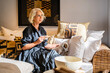 © Javier De La Torre/ADDICTIVE STOCK - Peaceful pensive mature female in elegant dress drinking coffee and stroking dog while relaxing on cozy soft sofa with cushions in stylish living room