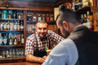 © Javier De La Torre/ADDICTIVE STOCK - Middle aged barkeeper looking at camera giving cocktail with raspberries to unrecognizable elegant bearded man while working in bar