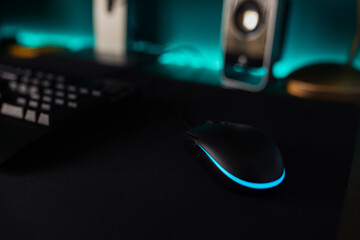 From above of black keyboard with blue illuminated letters placed on desk near computer monitor