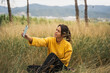 © Jordi Bataller/ADDICTIVE STOCK - Side view of charming female in yellow sweater sitting in dry field and taking selfie while entertaining at weekend in countryside