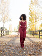 © Jose Carlos Cerdeno/ADDICTIVE STOCK - African American female with Afro hairstyle and in trendy silk overalls walking along wooden path in park and looking away