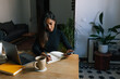 © Joy Zamora/ADDICTIVE STOCK - Indian female entrepreneur sitting at table and writing plans in notebook while working at home in cozy workplace