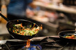 © Jose Carlos Cerdeno/ADDICTIVE STOCK - Skillet pan with fried vegetables being stirred by anonymous cook during preparation on gas stove in restaurant kitchen