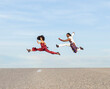 © Jose Carlos Cerdeno/ADDICTIVE STOCK - Side view of African American couple in trendy traditional clothes jumping high above asphalt road and performing dance on background of blue sky