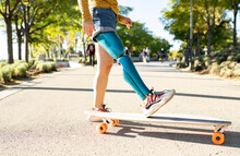 Crop Side View Of Positive Female With Leg Artificial Limb Of Leg Riding Longboard On Road In Summer
