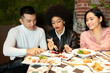 © Jose Carlos Cerdeno/ADDICTIVE STOCK - Multiracial group of young friends sitting at table with dishes together while having fun during dinner in cozy restaurant