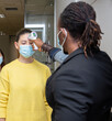 © Jose Carlos Cerdeno/ADDICTIVE STOCK - Woman in casual clothes and medical masks passing through procedure of body temperature control for coronavirus prevention before entering workplace