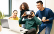 © Jose Carlos Cerdeno/ADDICTIVE STOCK - Unrecognizable black man with VR headset exploring virtual world while sitting at table with laptop surrounded by cheerful multiracial colleagues in modern workplace