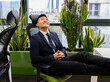 © Jose Carlos Cerdeno/ADDICTIVE STOCK - Side view of cheerful young Asian businessman in formal suit looking up and smiling dreamfully while thinking about successful business strategy in modern workspace