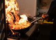© Jose Carlos Cerdeno/ADDICTIVE STOCK - Crop anonymous cook holding frying pan with burning flame while preparing meal with flambe in restaurant kitchen