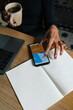 © Joy Zamora/ADDICTIVE STOCK - From above of crop anonymous female sitting at table with cup of coffee and analyzing diagram on smartphone while working on online project