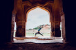 © Jose Kesada/ADDICTIVE STOCK - Side view of unrecognizable fit female in activewear performing Warrior I pose while practicing yoga near old arched oriental palace in mountainous terrain