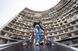 © Juan Alberto Ruiz/ADDICTIVE STOCK - From below of young female in casual outfit standing against multistory residential building with geometric curved walls on street of Kaohsiung city in Taiwan