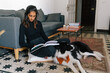 © Joy Zamora/ADDICTIVE STOCK - Thoughtful Indian female reading interesting story in book and sitting on floor with fluffy friendly Border Collie dog