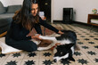 © Joy Zamora/ADDICTIVE STOCK - Smiling Indian female owner sitting on floor and playing with fluffy Border Collie dog