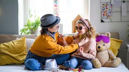 Wall Mural - Sisters indoors at home, playing on bed. Lockdown and dressing up concept.