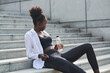 © Luis Gomez/ADDICTIVE STOCK - Side view of relaxed African American female runner sitting on stairs in city and holding bottle of fresh water during training