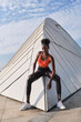 © Luis Gomez/ADDICTIVE STOCK - Confident African American sportswoman with slim body sitting on geometric construction in city and looking at camera