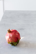 High Angle Of Single Fresh Ripe Red Whole Pomegranate Placed On Light Gray Table