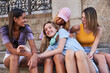 © Manuel Ruiz/ADDICTIVE STOCK - Group of cheerful multiracial teen girlfriends sitting on stone steps and having fun while spending summer day together in city