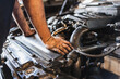 © Mar Godoy/ADDICTIVE STOCK - Cropped unrecognizable male mechanic with greasy hands checking motor of vehicle during work in garage