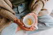 © Mauricio Garay/ADDICTIVE STOCK - From above of anonymous female sitting with cup of water with slice of fresh lemon in morning at home