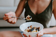 © Mauricio Garay/ADDICTIVE STOCK - Cropped unrecognizable female with tasty bowl of healthy granola sitting on floor at home and having nourishing breakfast