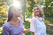 © Manuel Ruiz/ADDICTIVE STOCK - Happy young blond female with headphones on neck chatting with ethnic girlfriend while spending sunny summer day together and strolling in green park