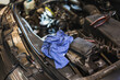 © Mar Godoy/ADDICTIVE STOCK - From above piece of dirty fabric placed under open car hood near battery during repair works in garage