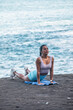 © Pablo Garcia/ADDICTIVE STOCK - Tranquil female practicing yoga in Bhujangasana on sandy beach near sea and looking away