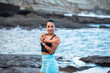 © Pablo Garcia/ADDICTIVE STOCK - Concentrated fit female in sports bra standing in seashore and warming up while stretching arms before training and looking away