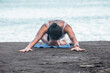 © Pablo Garcia/ADDICTIVE STOCK - Unrecognizable female sitting in Sleeping Swan pose on sandy shore and stretching body while doing yoga in summer