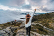 © Ruben Soto/ADDICTIVE STOCK - Back view of unrecognizable female traveler in hat standing with outstretch arms on rocks in mountains while enjoying freedom and nature