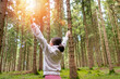 © Rob Wilkinson/ADDICTIVE STOCK - Side view of serene female traveler standing in woods with raised arms and enjoying early morning during adventure