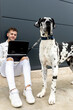 © Sergio Victor Vega/ADDICTIVE STOCK - Male freelancer sitting on street with Great Dane dog and working on remote project via laptop