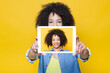 © Txema Gerardo/ADDICTIVE STOCK - Happy young African American female with curly hair taking selfie with digital tablet on bright yellow background
