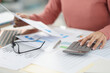 © megaflopp - Business woman counting on calculator and holding documents in hands closeup