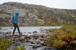 © Sergey Mironov/ADDICTIVE STOCK - Side view of female explorer in warm clothes crossing river while walking along wet stones in highland area during travel in autumn
