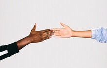 Close-up Of A Black Man's Hand Holding A White Woman's Hand Over White Background