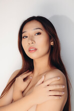Portrait Of Naked Young Chinese Woman Looking At Camera Over White Background